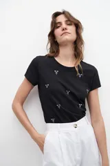 Remera blanca de algodón con cuello redondo y strass plateados formando pequeños dibujos.