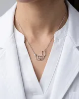 Collar de plata 925 con dije en forma de estetoscopio que integra un corazón con un electrocardiograma en su interior.