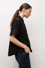 Camisa negra de manga corta, con cuello camisero clásico y cierre frontal de botones.