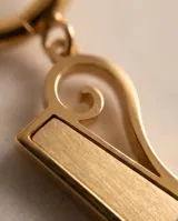 Caravanas de acero dorado con argolla pequeña y dije colgante en forma de barrita geométrica con detalle de espiral.