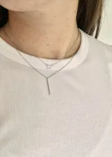 Collar plateado de doble cadena, con dije circular con circonitas y dije de barra vertical.