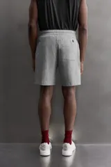 Pantalones cortos de algodón color gris, con cintura elástica ajustable con cordón y parche con logo. Incluye bolsillos laterales y un bolsillo trasero. Presenta bandas laterales a tono, bordado y estampado combinado a contraste en el delantero y la espalda, y aberturas laterales en el bajo.