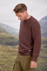 Sweater de punto grueso en color marrón, con cuello redondo y diseño de textura acanalada. Presenta un corte holgado y mangas largas.