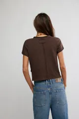 Remera de jersey suave color negro, de calce relajado, corte recto y largo corto, con escote en V y mangas cortas caídas con puño fijado.