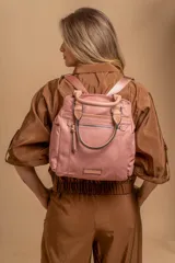 Cartera mochila de diseño versátil, color rosado, confeccionada en material sintético impermeable. Cuenta con doble asa superior, correas ajustables para usar como mochila, compartimento principal con cierre y bolsillo frontal con cierre decorado con tirador largo.