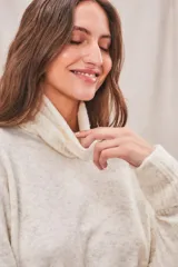 Sweater de punto color crema, con cuello alto y mangas largas.