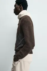 Jersey de punto marrón oscuro con diseño jacquard de rombos en gris y blanco, cuello redondo y manga larga.