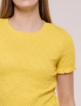 Blusa de calce al cuerpo con textura elastizada fruncida y diseño de rombos, cuello redondo de terminación ondulada, mangas cortas y ruedo con acabado ondulado.