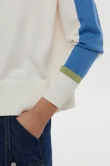 Sweater de punto color blanco con mangas raglán en azul y detalles en verde en los puños, cuello redondo y bordado de libélula en el pecho.