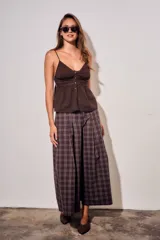 Pantalón de corte wide leg con diseño de cuadros, tiro medio y pinzas frontales que aportan volumen y movimiento a la prenda.