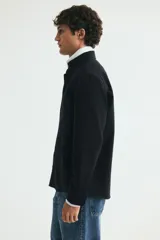 Camisa de algodón estilo Oxford, color negro, con cuello americano abotonado, bolsillo en el pecho y cierre frontal con botones blancos.