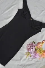 Vestido corto negro con breteles finos, escote en V y detalle de broderie en los bordes.