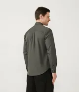 Camisa verde militar de manga larga en sarga de algodón, con cuello clásico, cierre frontal abotonado y dos bolsillos con solapa abotonada en el pecho.