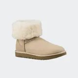 Botas de caña media UGG Classic Short II, confeccionadas en piel de oveja de doble cara color beige, con forro interior de lana suave y suela exterior liviana para mayor amortiguación.