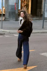 Chaqueta bomber de cuello redondo y manga larga, confeccionada en tejido de pelo sintético color marrón oscuro. Presenta cierre frontal con cremallera, bolsillos laterales y acabados elásticos en el ruedo y puños.