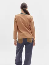 Remera de manga larga con cuello redondo y estampado a rayas horizontales en tonos marrón y negro. Tiene un logo bordado en el pecho de color rojo.