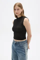 Top cropped negro de algodón, con cuello alto y diseño ajustado al cuerpo con frunces laterales.