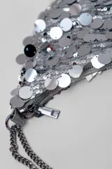 Cartera de mano tipo hobo con diseño de media luna, completamente cubierta de lentejuelas plateadas brillantes. Incluye una correa de cadena metálica plateada para llevar al hombro.