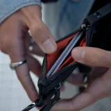 Billetera tipo pouch color negro, fabricada en material impermeable xPac X21. Cuenta con cierre principal, bolsillo frontal con cierre y tiradores ergonómicos. Incluye tecnología de bloqueo RFID.