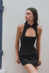 Vestido mini negro sin mangas, con cuello mao, abertura frontal tipo lágrima y forro interior a tono. Cierre en la espalda con cremallera oculta.