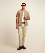 Pantalón de vestir color marrón, de corte slim y largo cropped. Confeccionado en tejido de algodón liso, con bolsillos laterales y traseros. Cierre frontal con botón y cremallera.