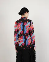 Camisa de manga larga con estampado floral multicolor sobre fondo negro, cuello clásico y cierre frontal de botones.