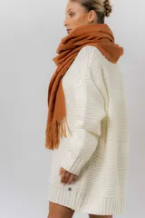 Buzo tipo sweater de punto color blanco, con diseño de trenzas verticales, cuello redondo, mangas largas y tajos laterales. Presenta un corte oversize y largo extendido.