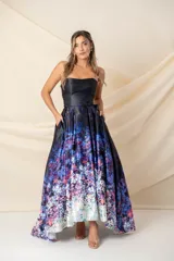 Vestido largo strapless con corpiño negro y falda estampada con degradé floral en tonos azules, violetas y blancos. Falda amplia con tablas y bolsillos, armada con tul y más larga atrás. Incluye cinturón azul con hebilla circular. Modelo único.