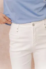 Pantalón jean de tiro alto y corte wide leg, color off white. Presenta un diseño minimalista con bolsillos funcionales, cierre frontal con botón y detalles metálicos plateados.
