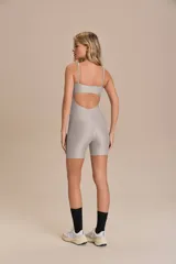 Jumpsuit corto de diseño ajustado con escote cuadrado y breteles finos. Confeccionado en tejido técnico con acabado ligeramente brillante y textura acanalada, ofrece compresión media y alta elasticidad.