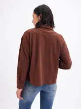 Campera de pana color beige, con cuello camisero, cierre frontal de botones oscuros, mangas largas con puños abotonados y dos bolsillos frontales con solapa.
