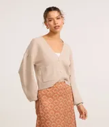 Cardigan corto de punto color beige con escote en V, cierre frontal con botones, mangas abullonadas y bolsillos frontales aplicados.