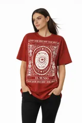 Remera de algodón de manga corta y cuello redondo, con diseño holgado y estampado frontal con motivos florales y texto.