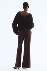 Pantalón sastrero de corte acampanado, con cierre frontal, botón oculto y corchetes. Presenta bolsillos al bies, bolsillos traseros ribeteados y pliegues marcados tanto en la parte delantera como en la trasera.