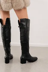 Bota bucanera de cuero genuino color negro, con caña alta sobre la rodilla, taco cuadrado bajo y cierre lateral.