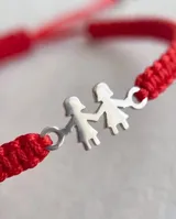 Pulsera de hilo rojo trenzado en macramé, con dije central de plata 925 con diseño de dos nenas tomadas de la mano y cierre regulable.
