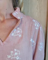 Blusa de algodón color azul, de corte suelto, con mangas largas abullonadas y cuello con volados y escote en V.
