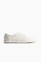 Championes de lona de algodón en color blanco, con cordones, suela de goma y diseño clásico.
