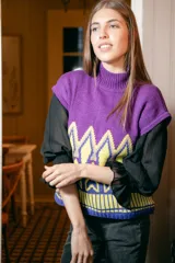 Chaleco de punto morado con cuello alto y estampado geométrico amarillo y azul.