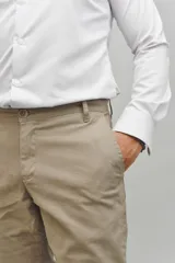 Pantalón de gabardina color beige, de corte recto y tiro medio, con cierre frontal de botón y cremallera.