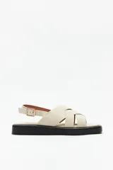 Sandalias color beige con capellada entrelazada y agarre ajustable en el talón. Plataforma de 3cm de alto y suela negra.