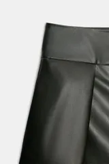Shorts de tiro alto y efecto piel en color negro, con pliegues en la parte delantera y cierre frontal con cremallera y ganchos metálicos.