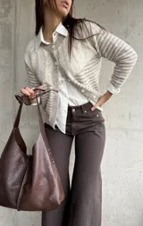 Cardigan de punto con diseño de rayas horizontales en tonos beige y blanco, cuello redondo y cierre frontal con botones. Presenta mangas largas con puños ajustados.