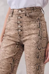 Pantalón de jean de corte recto con estampado de piel de serpiente en tonos beige y marrón. Tiene tiro medio y cierre frontal con botones.