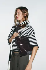 Bolso maxi shopper color marrón oscuro, con asa ancha ajustable con hebilla. Incluye bolsillo interno con cierre de cremallera metálica y cierre imantado.