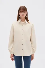 Campera marrón de manga larga confeccionada en algodón, con cuello camisero, cierre frontal con botones a presión y puños elásticos fruncidos.