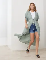 Kaftan largo color verde salvia, con mangas cortas y detalle de puntilla bordada en el área del busto y cintura. Posee un lazo ajustable en el centro del frente.