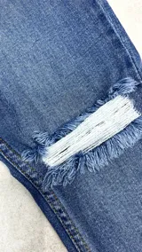 Pantalón de jean chupín color azul claro con roturas en ambas rodillas y en el muslo.