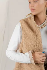 Chaleco de corderito color tostado, con cuello alto y diseño sin mangas.