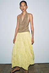 Falda larga de tiro medio color amarillo, con cintura elástica, diseño plisado y bajo asimétrico.